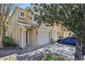 Inviting condo exterior showcasing attached garages and a well-manicured landscape, shaded by a large tree at 2679 Metro Sevilla Dr # 101, Orlando, FL 32835