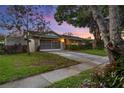 Single-story home with a well-manicured lawn, driveway, mature trees, and an attached two-car garage with a screen door at 4991 Tangerine Ave, Winter Park, FL 32792