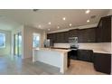 Modern kitchen featuring stainless steel appliances, dark cabinetry and a white island with seating at 7020 Rolling Leaf Dr, Groveland, FL 34736