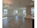 Open floor plan showcasing tile flooring, neutral paint, bright light fixtures, and large windows at 7020 Rolling Leaf Dr, Groveland, FL 34736