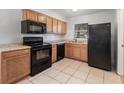 Functional kitchen featuring tile floors, wooden cabinets, and black appliances at 7906 Arabian Pl, Orlando, FL 32818