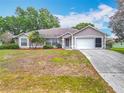 Single-story house with a two-car garage, neutral paint, mature trees, and manicured landscaping at 11512 Grand Bay Blvd, Clermont, FL 34711