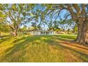 Charming single-story home with spacious front yard featuring mature trees and lush green lawn at 141 Greenfield Rd, Winter Haven, FL 33884