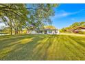 Well-maintained single-story home featuring a spacious front yard, mature trees and an inviting landscape at 141 Greenfield Rd, Winter Haven, FL 33884
