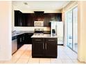 Modern kitchen with stainless steel appliances, granite counters, and dark wood cabinets at 2144 Rookery Ln, Sanford, FL 32773