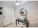 Bright foyer with a white door, console table, decorative mirror, and tile flooring at 2804 Polvadero Ln # 107, Orlando, FL 32835