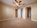This bedroom includes neutral carpet, a ceiling fan, a closet, and access to a bathroom at 4504 Messina Dr, Lake Mary, FL 32746