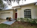 Front exterior view with attached garage, red front door, large window, and planted bushes at 5342 Rabbit Ridge Trl, Orlando, FL 32818
