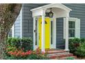 View of front entrance highlighting a bright yellow door, red brick steps and manicured landscaping at 1701 Delaney Ave, Orlando, FL 32806