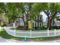 Landscaped two-story home featuring a white picket fence and a vibrant yellow front door at 1701 Delaney Ave, Orlando, FL 32806