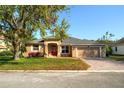 Inviting single-story home featuring a well-manicured lawn, a brick driveway, and a bright red front door at 1924 Eloise Cove Dr, Winter Haven, FL 33884