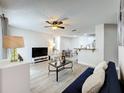 Bright living room featuring new gray laminate flooring and a ceiling fan at 2580 Grassy Point Dr # 100, Lake Mary, FL 32746