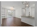 Spacious living room featuring an open design, dark laminate floors, modern light fixtures, and a view of the balcony at 2717 Maitland Crossing Way # 205, Orlando, FL 32810