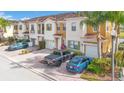 A row of townhomes with brick paved driveways with multiple cars parked and palm trees in the landscaping at 3466 Allegra Cir, St Cloud, FL 34772