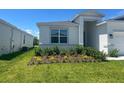 Well-maintained lawn, complemented by garden beds featuring shrubs, and a view of the home's front exterior at 4086 Gooseberry Trl, Kissimmee, FL 34746