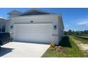 Two car garage with a concrete driveway and manicured lawn at 4086 Gooseberry Trl, Kissimmee, FL 34746