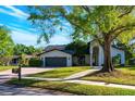 Charming home exterior showcasing a two-car garage and a meticulously maintained front lawn at 5101 The Oaks Cir, Orlando, FL 32809