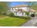 A spacious home features a well-manicured lawn and side-entry garage, surrounded by lush landscaping at 6030 Greatwater Dr, Windermere, FL 34786