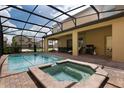 Outdoor pool and spa under screened enclosure with patio seating, grill, and sunny views at 8801 Rhodes St, Kissimmee, FL 34747