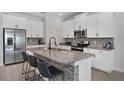 Modern kitchen featuring white cabinets, granite countertops, stainless steel appliances and breakfast bar at 10509 Authors Way, Orlando, FL 32832