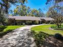 Long driveway leads to a stone facade house surrounded by lush landscaping and mature trees on a sunny day at 3431 Dawn Ct, Lake Mary, FL 32746