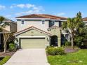 A two-story home with a terra cotta tile roof, front yard landscaping, and an attached two-car garage at 5283 Wildwood Way, Davenport, FL 33837