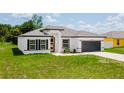 Charming one-story home boasts a modern exterior design, lush green lawn, and well-manicured landscaping at 6164 Sw 129Th St, Ocala, FL 34473