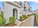 Charming townhome featuring an arched entryway and wrought iron balcony, complemented by lush landscaping at 62 W Jersey St # 13, Orlando, FL 32806