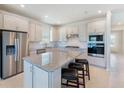 Modern kitchen features stainless steel appliances, white cabinets, an island, and stylish bar stools at 6403 Shimmering Shores Ln, St Cloud, FL 34771