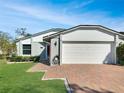View of the two-car garage, a brick driveway, and a green lawn of a well-maintained one-story home at 120 Mayfair Ct # 120, Sanford, FL 32771