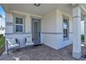 Inviting front porch features neutral chairs, brick flooring, and a blue front door at 14317 Lanikai Beach Dr, Orlando, FL 32827