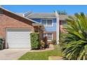 Townhouse exterior featuring brick facade, white garage door, and a walkway surrounded by greenery at 17 Lawn St, Oviedo, FL 32765