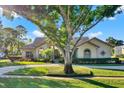 Well-maintained single-story home with a circular driveway and manicured landscaping, framed by a large tree at 2230 Lake Crescent Ct, Windermere, FL 34786