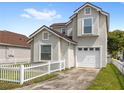Inviting two-story home featuring a white picket fence, tidy lawn, and an attached garage at 2361 Carriage Run Rd, Kissimmee, FL 34741