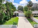 Aerial view of a charming home with mature trees, manicured lawn, and a long driveway leading to the garage at 322 N Rhodes St, Mount Dora, FL 32757