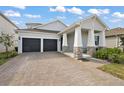 Inviting home with a two-car garage, a welcoming front porch with stone accents, and a neatly paved driveway at 4439 Davos Dr, Clermont, FL 34711