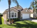 Charming home boasts a tile roof, two-car garage, lush lawn, and mature palm trees enhancing its curb appeal at 631 Tuscan Hills Blvd, Davenport, FL 33897