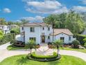 Elegant stucco home with a red tile roof, framed by palm trees and a circular driveway offering ample parking space at 1630 Lasbury Ave, Winter Park, FL 32789