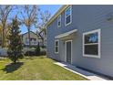 Side view of a light blue two-story townhome with green grass, a small tree, and a charming front door at 2037 Canny Cv, Winter Park, FL 32792