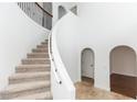 Bright foyer showcasing a curved staircase with neutral carpet and wrought iron railing, complemented by archways at 2217 Wekiva Reserve Blvd, Apopka, FL 32703