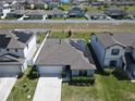 Aerial shot of a single-story home with solar panels, a two-car garage, and well-manicured landscaping at 297 Citrus Isle Loop, Davenport, FL 33837