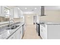 Modern kitchen with stainless steel appliances, light stone countertops, and white cabinets at 321 Ferdinand Dr, Longwood, FL 32750