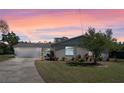 Charming single-story home with a spacious driveway, manicured lawn, and vibrant landscaping during sunset at 1021 Mare Bello Dr, Winter Park, FL 32792