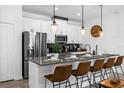 Modern kitchen featuring stainless steel appliances, stylish pendant lighting, and a breakfast bar with seating at 1106 Kingsbarn St, Davenport, FL 33896