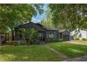 Well-maintained one-story home showcasing a dark facade, green lawn, and mature trees, set in a tranquil neighborhood at 1432 W Yale St, Orlando, FL 32804