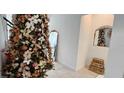 Festive Christmas tree decorates this living room adjacent to staircase and arched mirror at 15742 Vetta Dr, Bella Collina, FL 34756