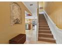 Inviting foyer with travertine floors, arched display niche, and staircase leading to the upper level at 2864 Polana St # 104, Orlando, FL 32835