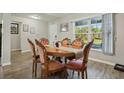 Bright dining room features a round table and six ornate chairs, illuminated by a large window with wooded outdoor views at 3176 Sw 127Th St, Ocala, FL 34473