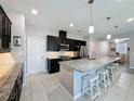 Modern kitchen featuring dark cabinets, stainless steel appliances, and a large island with counter seating at 434 Alcove Dr, Groveland, FL 34736