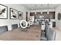 Elegant dining space featuring a wooden table, modern chairs, artwork, and pendant lighting above a kitchen counter at 7740 Sandy Ridge Dr # 136, Reunion, FL 34747